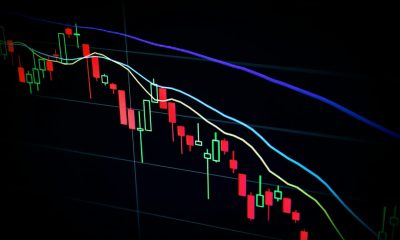 Stock market candlestick chart on dark screen showing decline