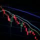 Stock market candlestick chart on dark screen showing decline