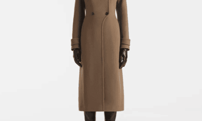 Brown double-breasted wool coat with an overlapped collar and a curved front hem that sweeps away from the button closure.